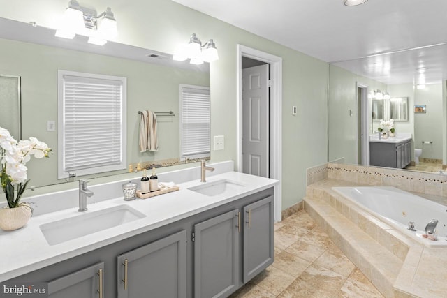 bathroom with vanity and tiled bath