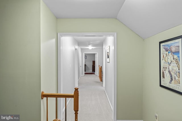 hallway featuring lofted ceiling and light carpet