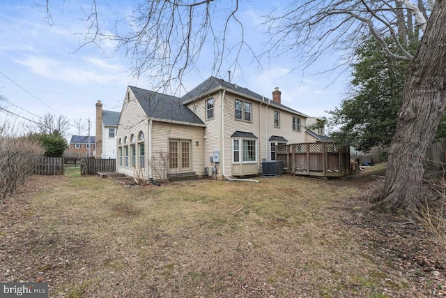 back of property with central AC unit and a yard