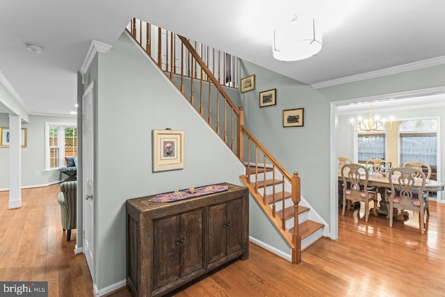 staircase featuring ornamental molding, wood-type flooring, and a notable chandelier