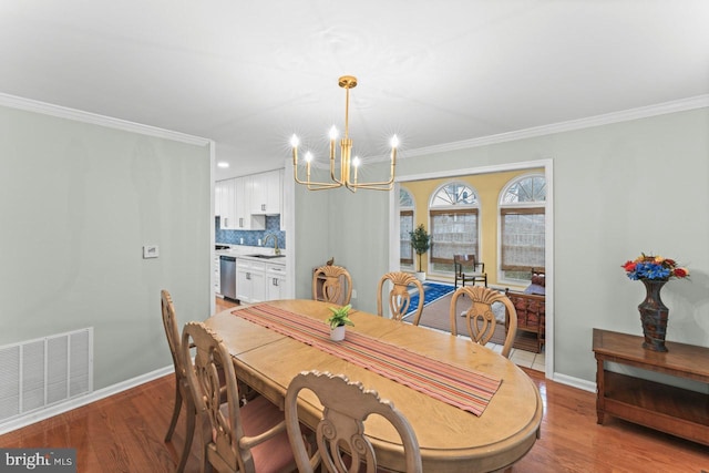 dining space with ornamental molding, sink, a chandelier, and light hardwood / wood-style floors