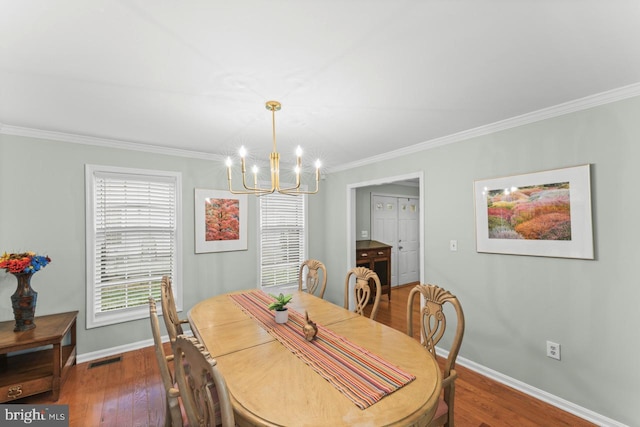 dining area with dark wood-type flooring, crown molding, and a chandelier