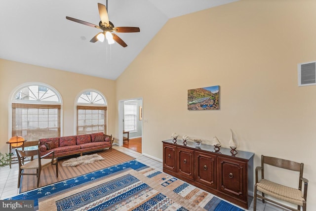 living room with ceiling fan, plenty of natural light, light tile patterned flooring, and high vaulted ceiling