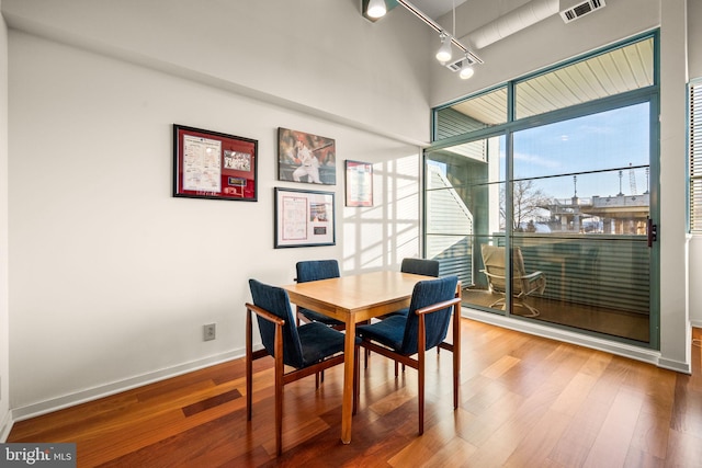 dining room with baseboards, visible vents, track lighting, and wood finished floors