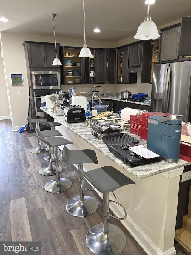 kitchen with dark brown cabinetry, pendant lighting, a breakfast bar, and appliances with stainless steel finishes