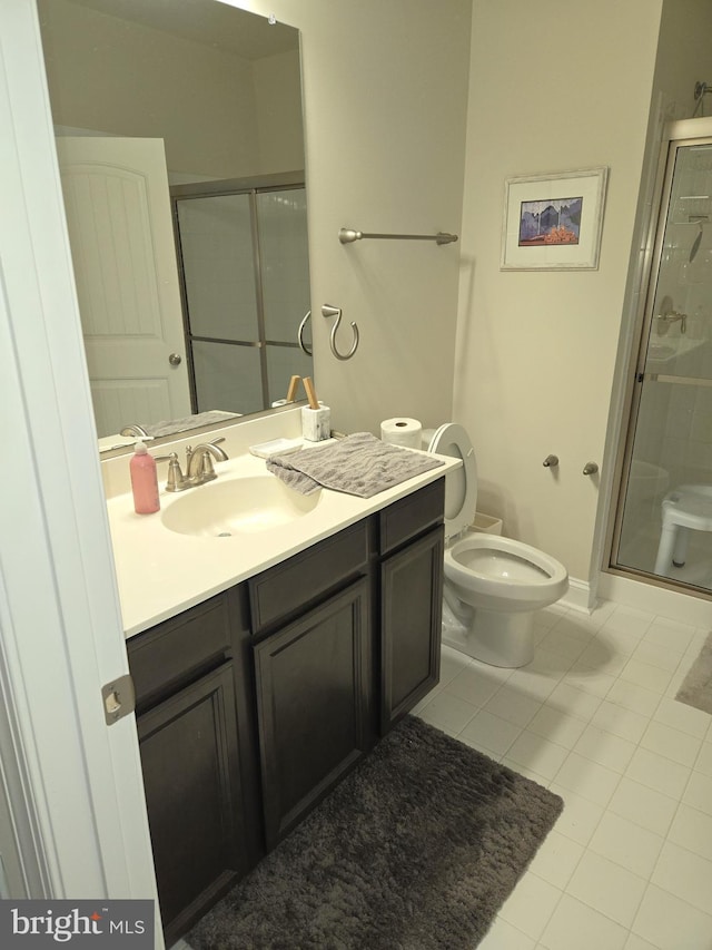 bathroom with a shower with door, vanity, tile patterned flooring, and toilet