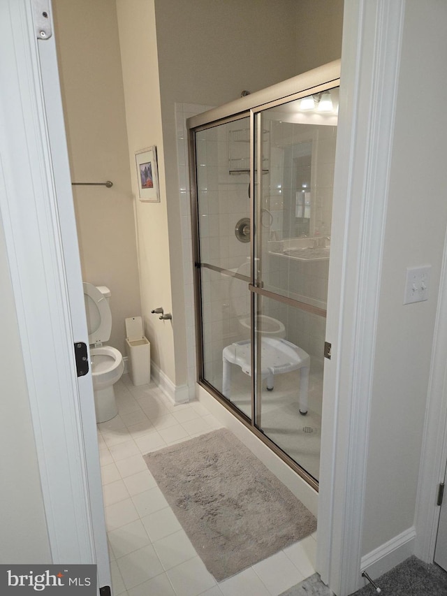 bathroom with tile patterned flooring, a shower with shower door, and toilet