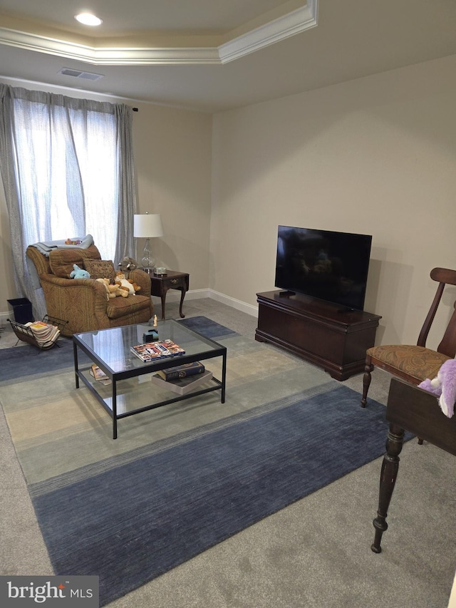 carpeted living room with a raised ceiling and ornamental molding