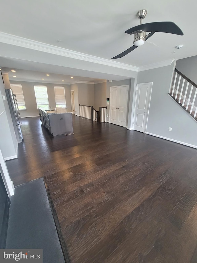 unfurnished living room featuring dark wood-type flooring, ceiling fan, and ornamental molding