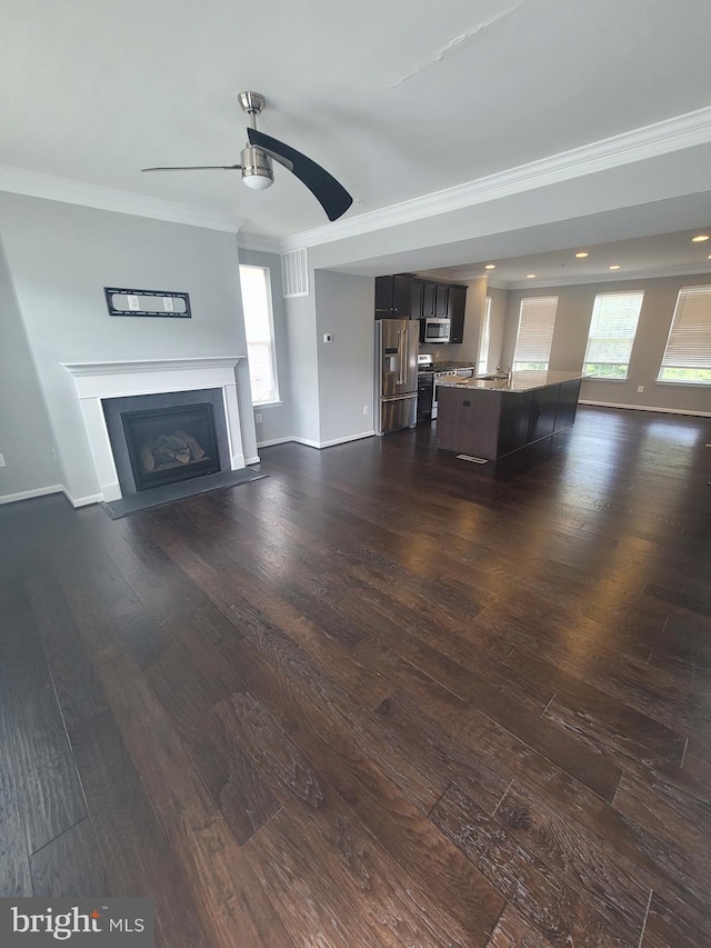 unfurnished living room with crown molding, dark wood-type flooring, and ceiling fan