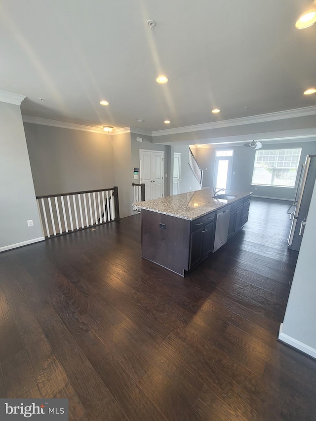 kitchen featuring dark wood-type flooring, sink, a center island with sink, ornamental molding, and light stone countertops