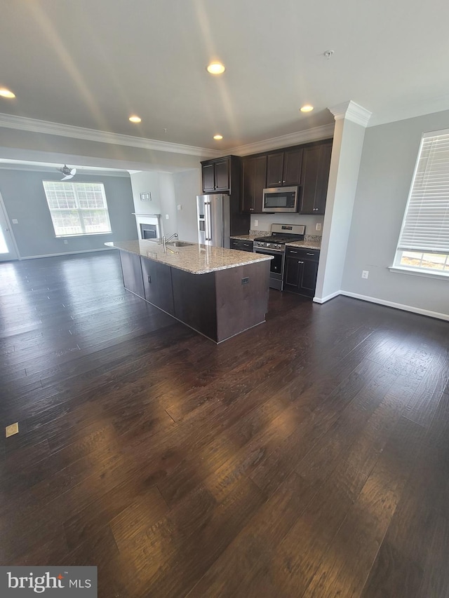 kitchen with crown molding, appliances with stainless steel finishes, a kitchen island with sink, dark brown cabinets, and dark hardwood / wood-style flooring