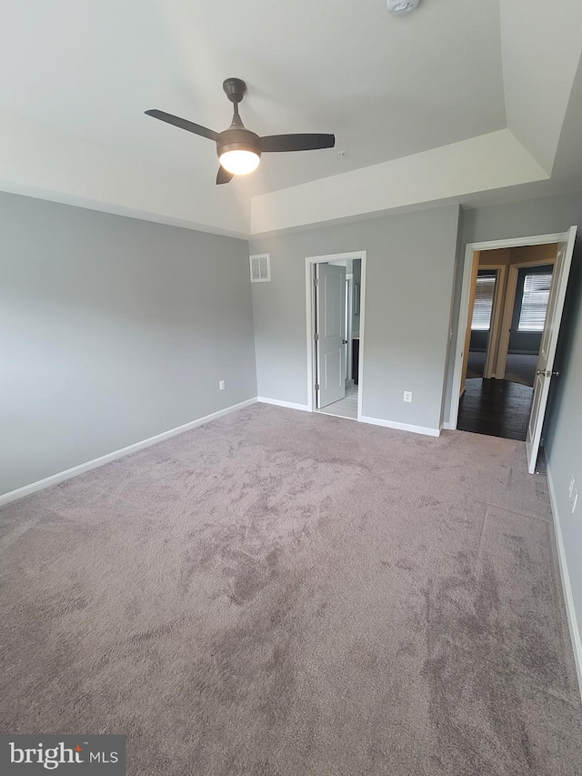 unfurnished bedroom featuring light colored carpet, ceiling fan, and a tray ceiling