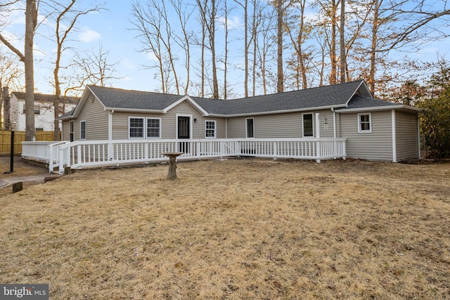 ranch-style home with a front yard, fence, and roof with shingles