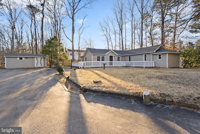 single story home with an outbuilding, driveway, and a wooden deck