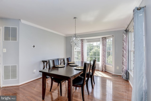 dining area featuring crown molding, an inviting chandelier, and light hardwood / wood-style flooring