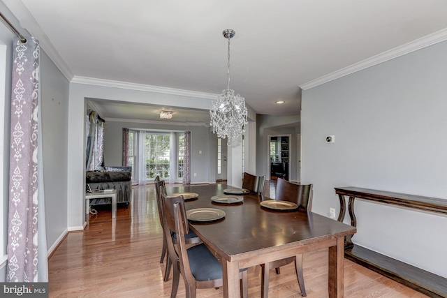 dining space featuring crown molding, hardwood / wood-style flooring, and an inviting chandelier