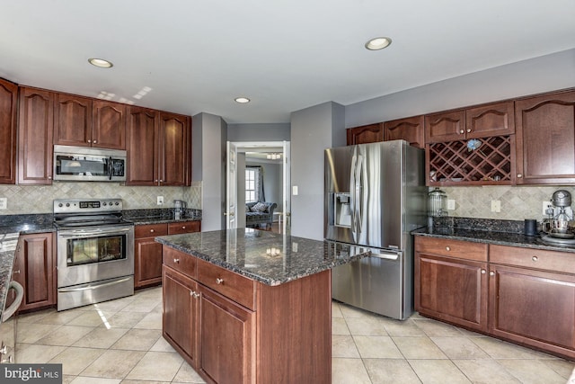 kitchen featuring a kitchen island, light tile patterned flooring, dark stone counters, and appliances with stainless steel finishes