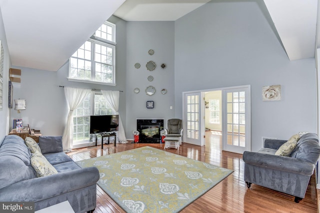 living room with french doors, a fireplace, hardwood / wood-style floors, and a high ceiling