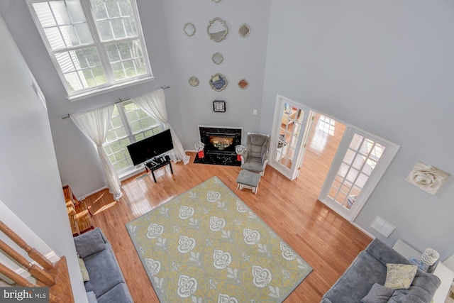 living room featuring a towering ceiling, a high end fireplace, and light wood-type flooring