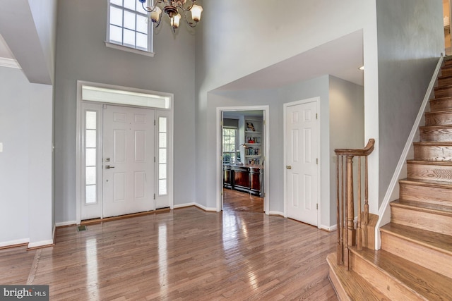 entrance foyer with hardwood / wood-style flooring, a towering ceiling, and a notable chandelier