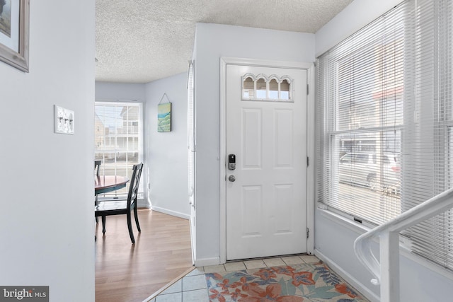 foyer with light tile patterned floors and a textured ceiling