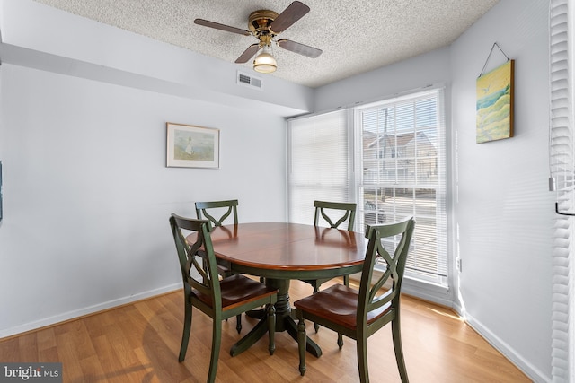 dining space with ceiling fan, a textured ceiling, and light wood-type flooring