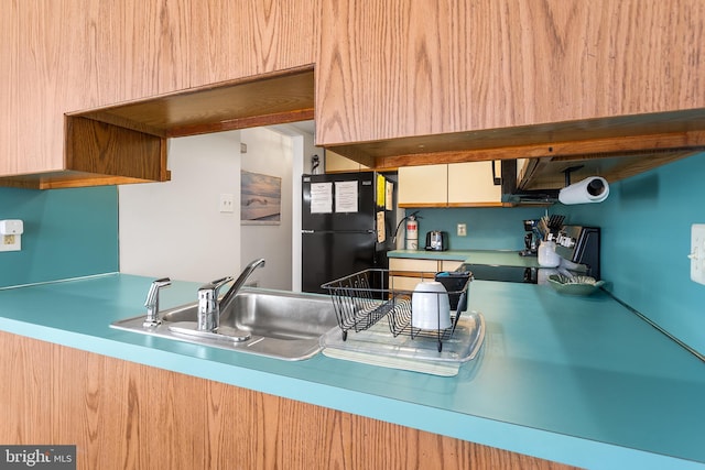 kitchen featuring stove, sink, and black fridge