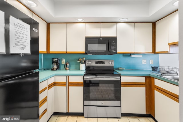 kitchen featuring light tile patterned flooring, white cabinets, and black appliances