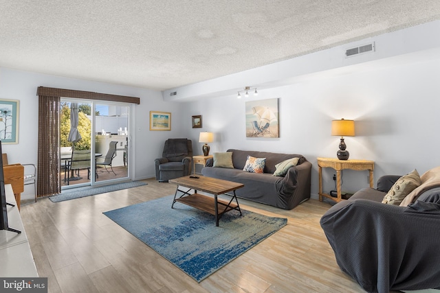 living room with a textured ceiling and light wood-type flooring