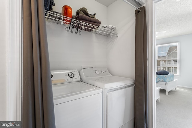 clothes washing area featuring washing machine and dryer, a textured ceiling, and carpet