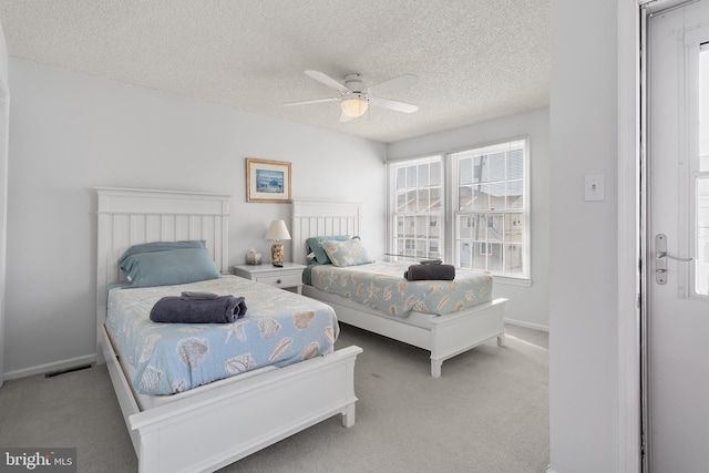 bedroom featuring ceiling fan, light carpet, and a textured ceiling