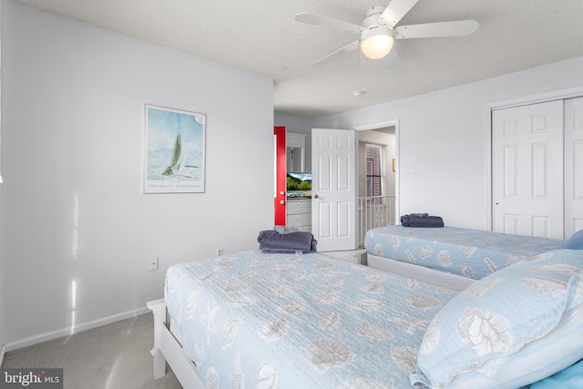 carpeted bedroom featuring ceiling fan, a closet, and a textured ceiling