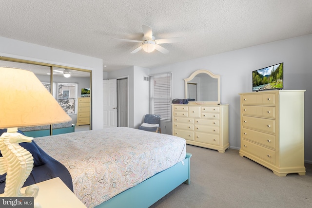 bedroom with ceiling fan, light colored carpet, and a textured ceiling