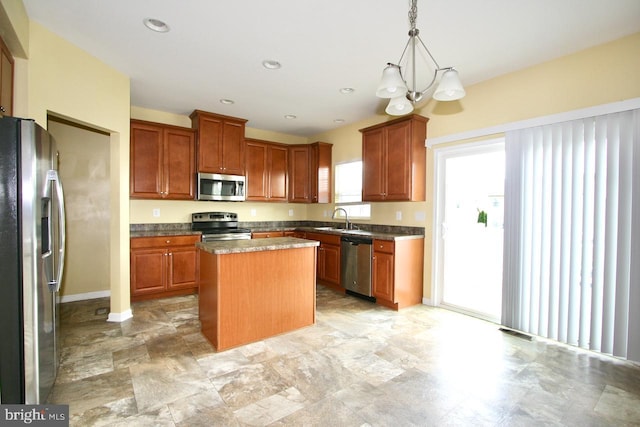 kitchen with hanging light fixtures, sink, a center island, and appliances with stainless steel finishes