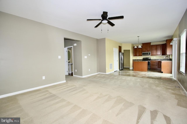 unfurnished living room with sink, light carpet, and ceiling fan