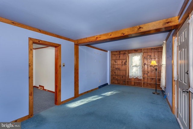 carpeted empty room featuring beamed ceiling