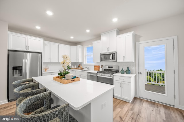 kitchen featuring white cabinetry, a kitchen bar, a kitchen island, and appliances with stainless steel finishes