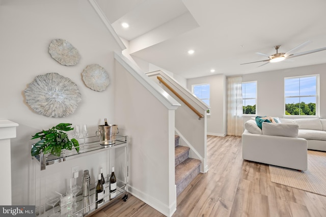 stairs with hardwood / wood-style floors and ceiling fan