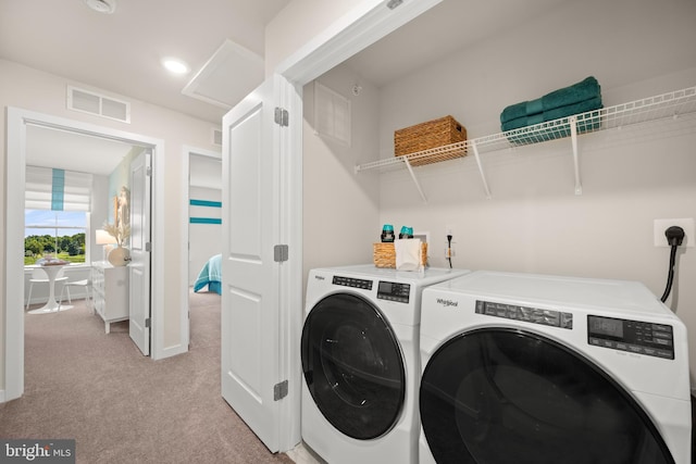 clothes washing area featuring light carpet and independent washer and dryer