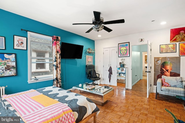 bedroom with light parquet floors, ceiling fan, and a closet