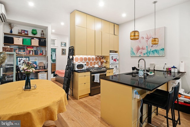 kitchen featuring sink, a kitchen bar, light hardwood / wood-style floors, kitchen peninsula, and gas range