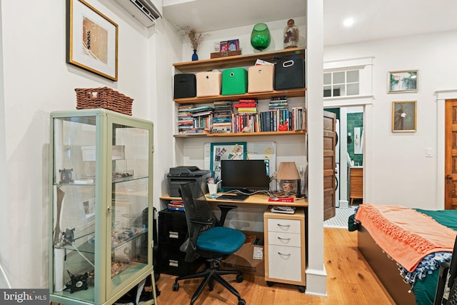 office area with light hardwood / wood-style floors and an AC wall unit