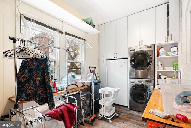 clothes washing area with cabinets, stacked washer / dryer, and dark hardwood / wood-style floors