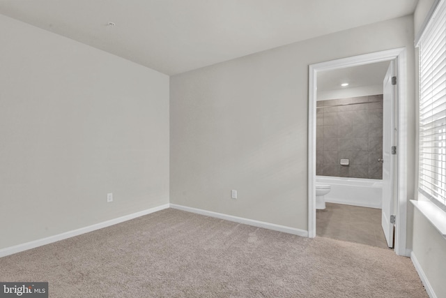 unfurnished bedroom with ensuite bath and light carpet