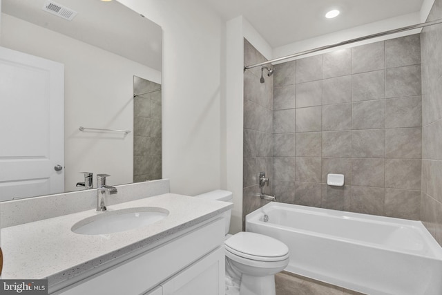 full bathroom with tiled shower / bath combo, vanity, and toilet