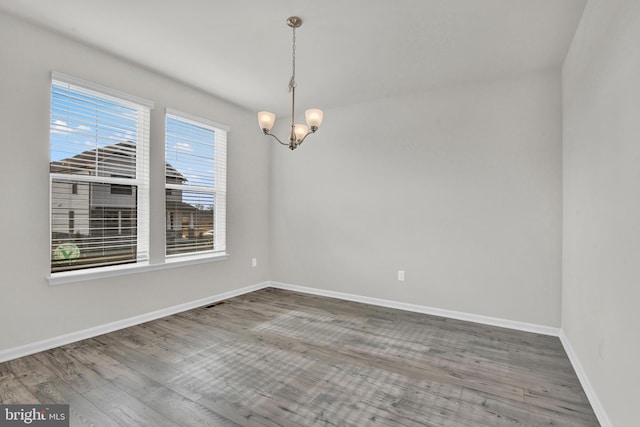 spare room featuring an inviting chandelier and hardwood / wood-style flooring