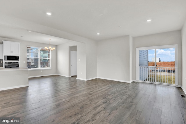 unfurnished living room featuring dark hardwood / wood-style floors and a notable chandelier