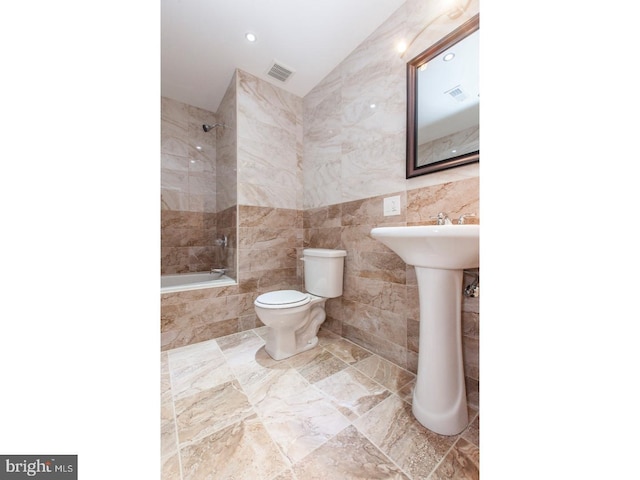 full bathroom with tile walls, sink, toilet, and tiled shower / bath