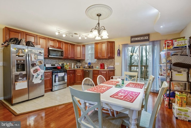 kitchen featuring a chandelier, hanging light fixtures, light hardwood / wood-style flooring, stainless steel appliances, and decorative backsplash